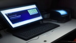 A gamer in a VR headset with motion controllers stands in a futuristic gaming room lit by RGB lights beside a high-end PC and immersive gear
